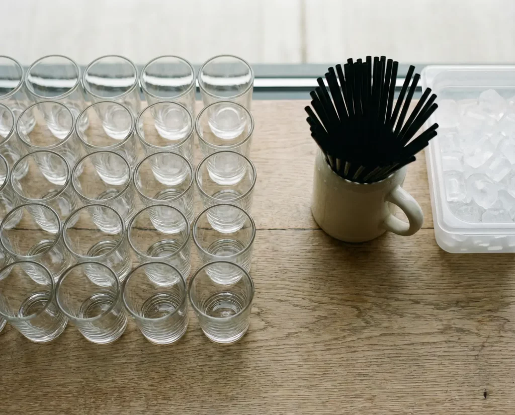 Gläser, Eiswürfel und Strohhalme ordentlich vorbereitet auf einem Tresen.